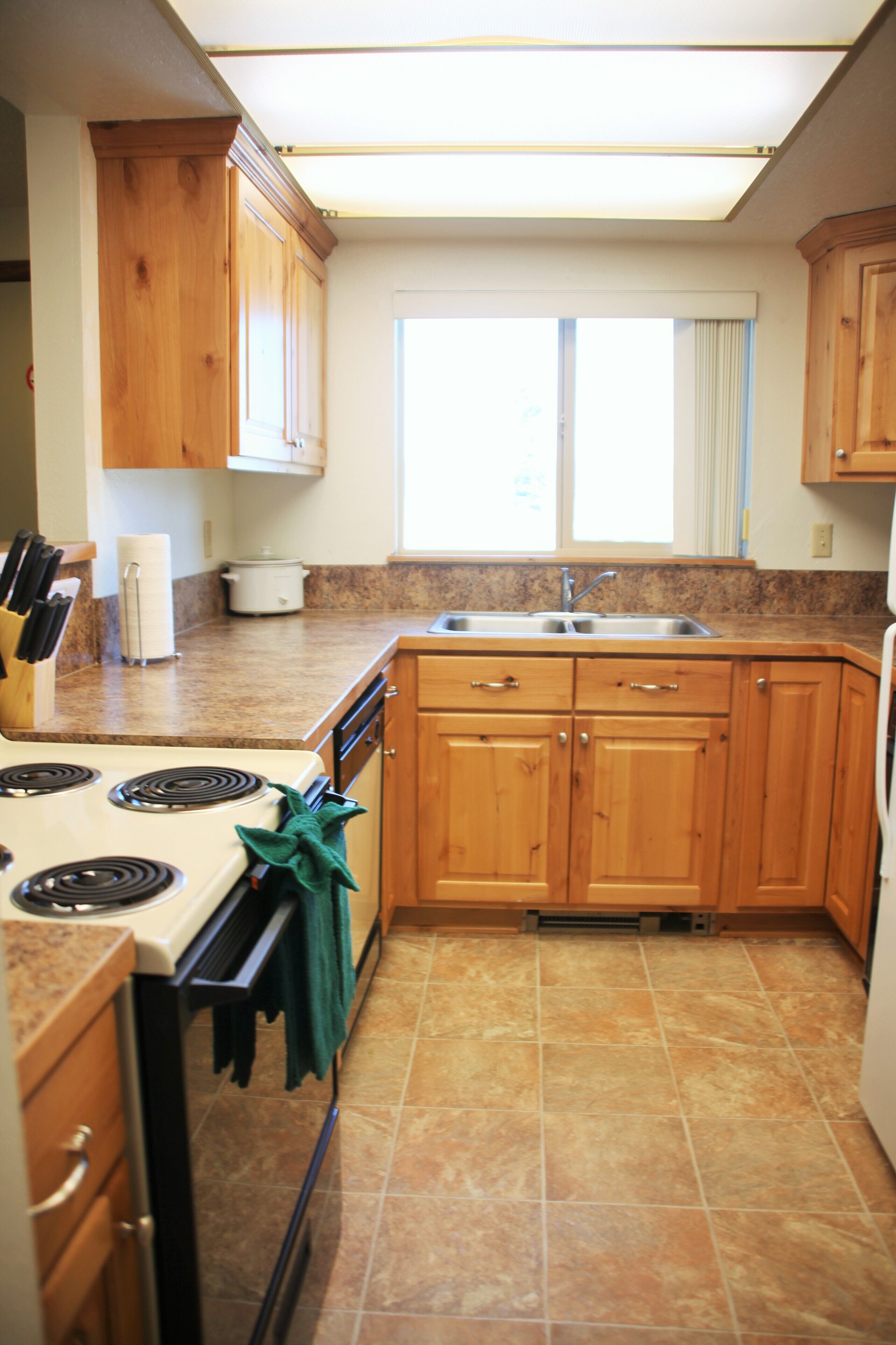 A kitchen with wooden cabinets, a stove, and a sink.