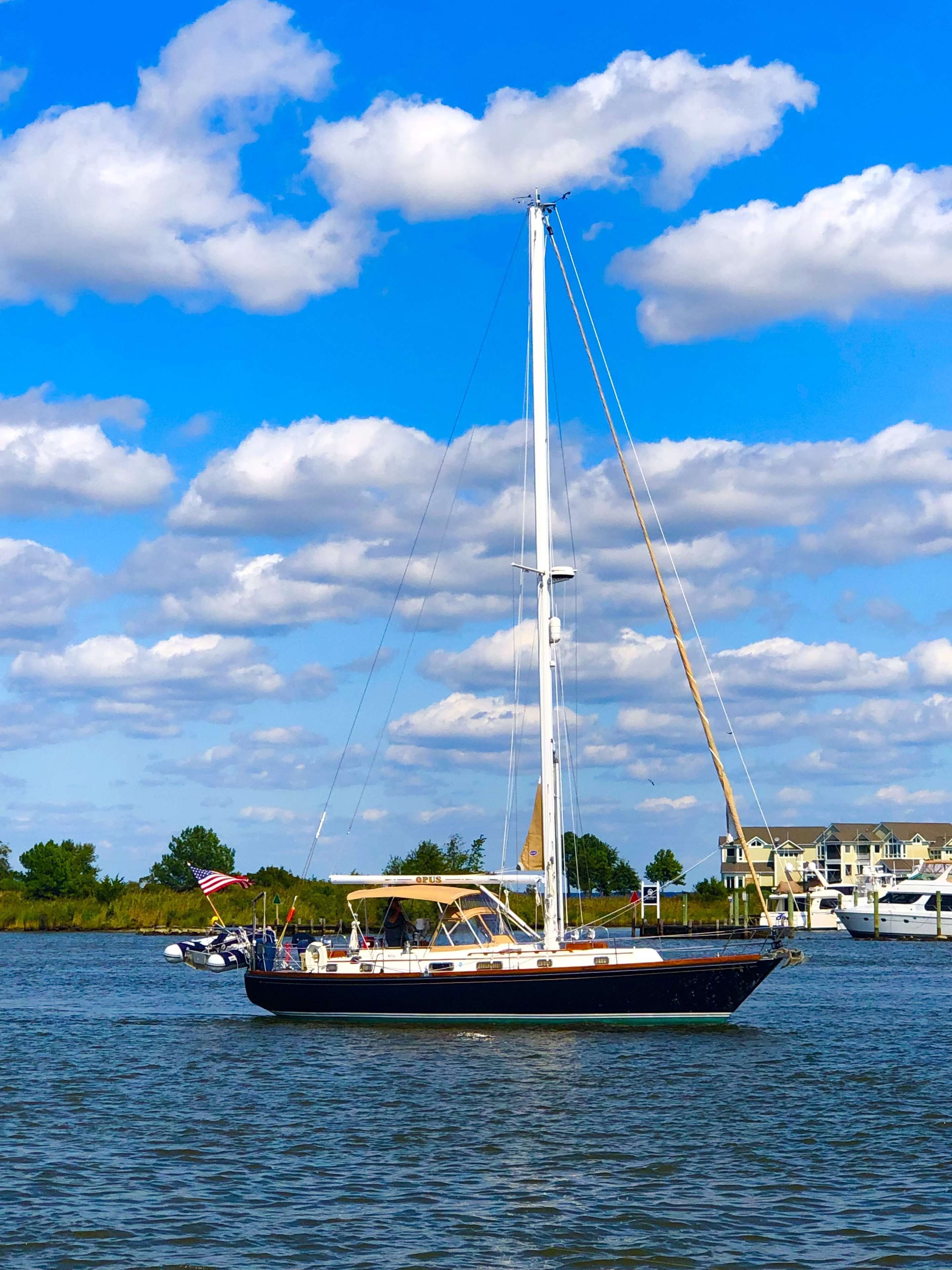 Un velero en el agua, con cielo despejado y nubes al fondo.
