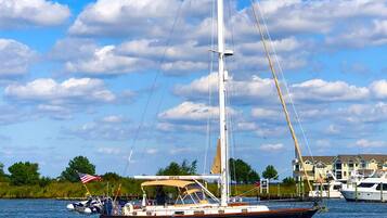 Un velero en el agua, con cielo despejado y nubes al fondo.