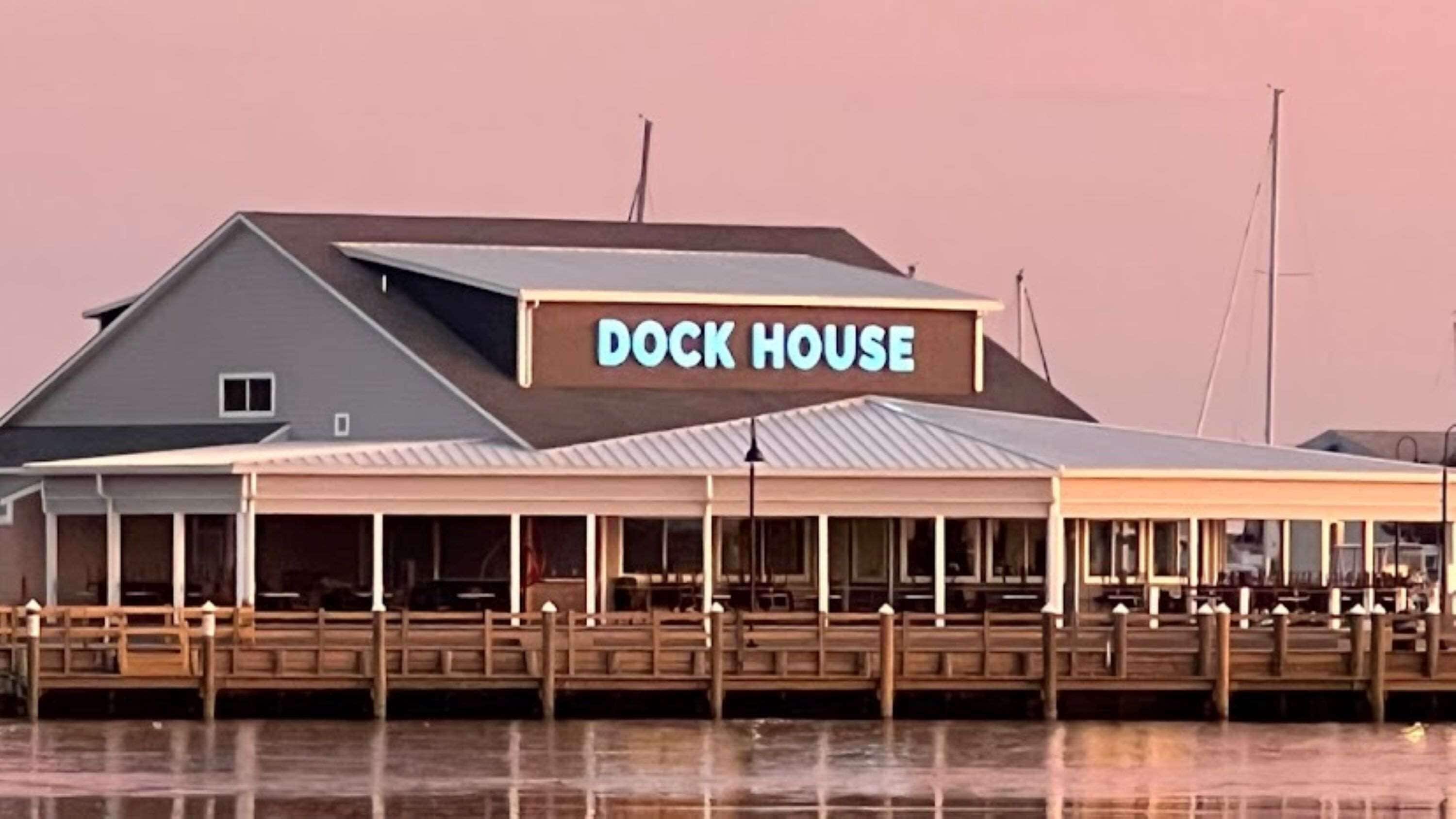 Una casa sul molo con un'area salotto esterna coperta e un cartello che riporta la scritta "DOCK HOUSE".