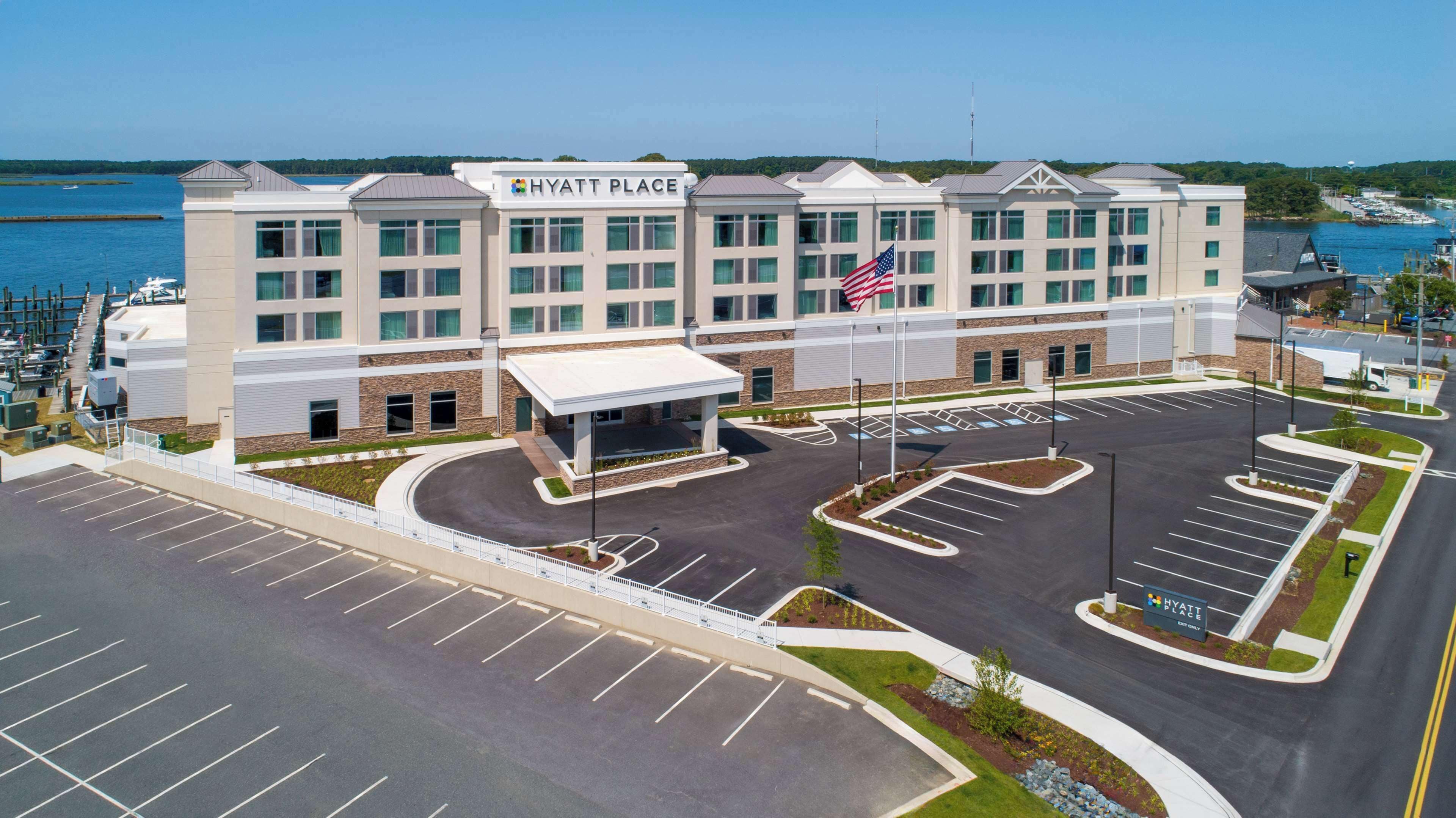 A Hyatt Place hotel with a parking lot, a covered entrance, and a view of the water.
