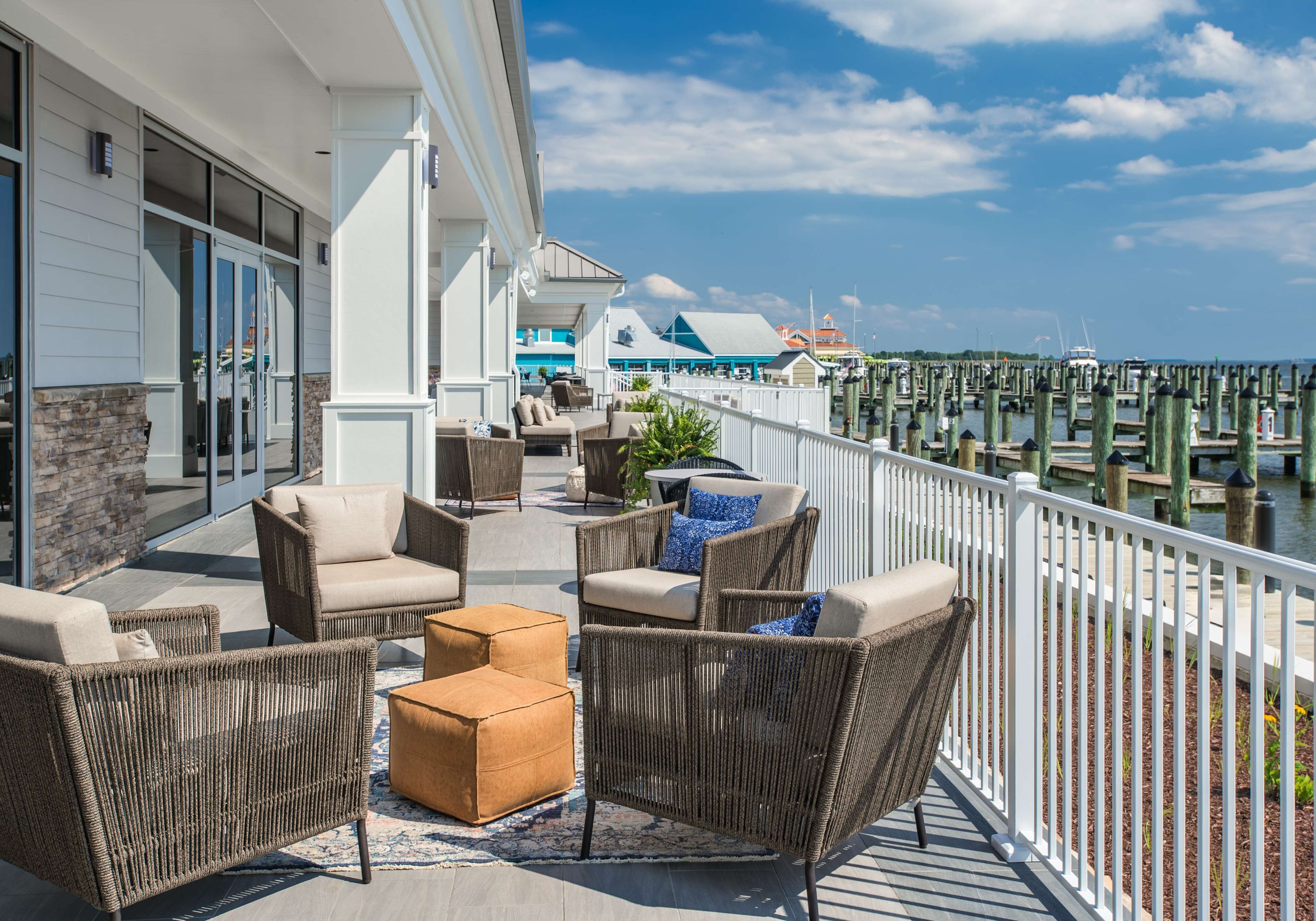 A balcony with wicker furniture, a stone wall, and a view of the marina.