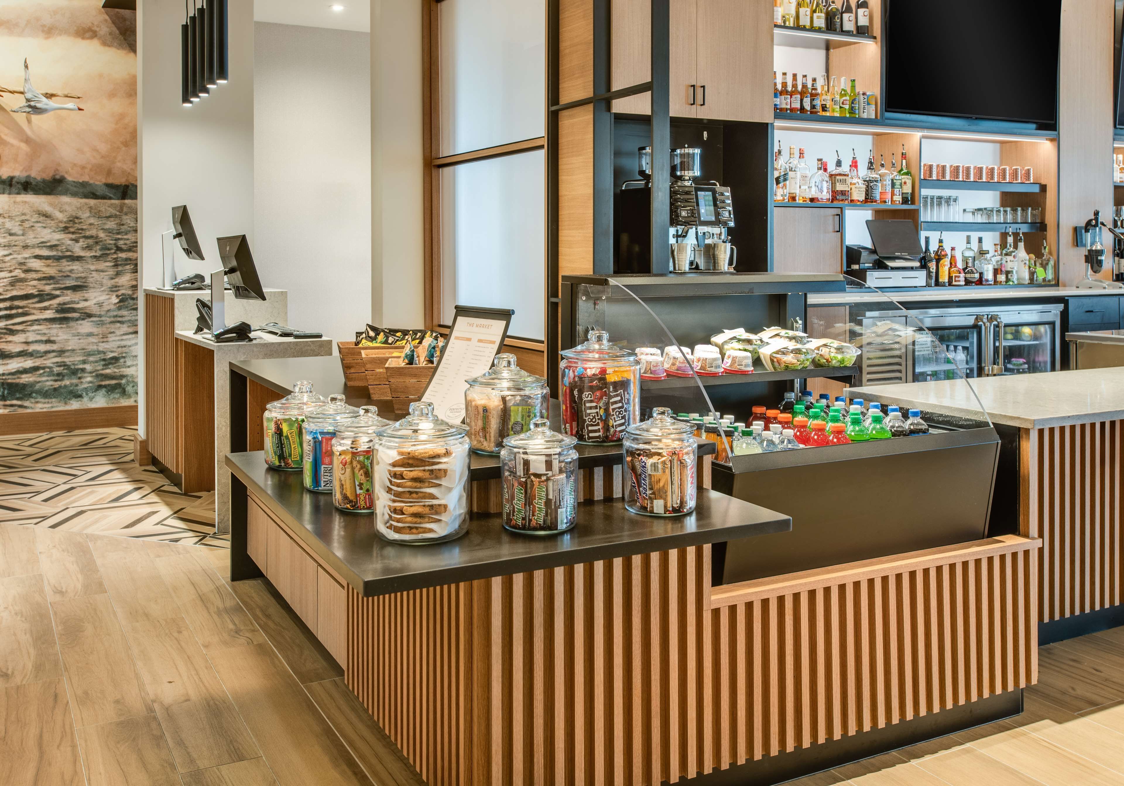 A hotel reception area with a counter displaying snacks and beverages, a coffee machine, and a television screen.