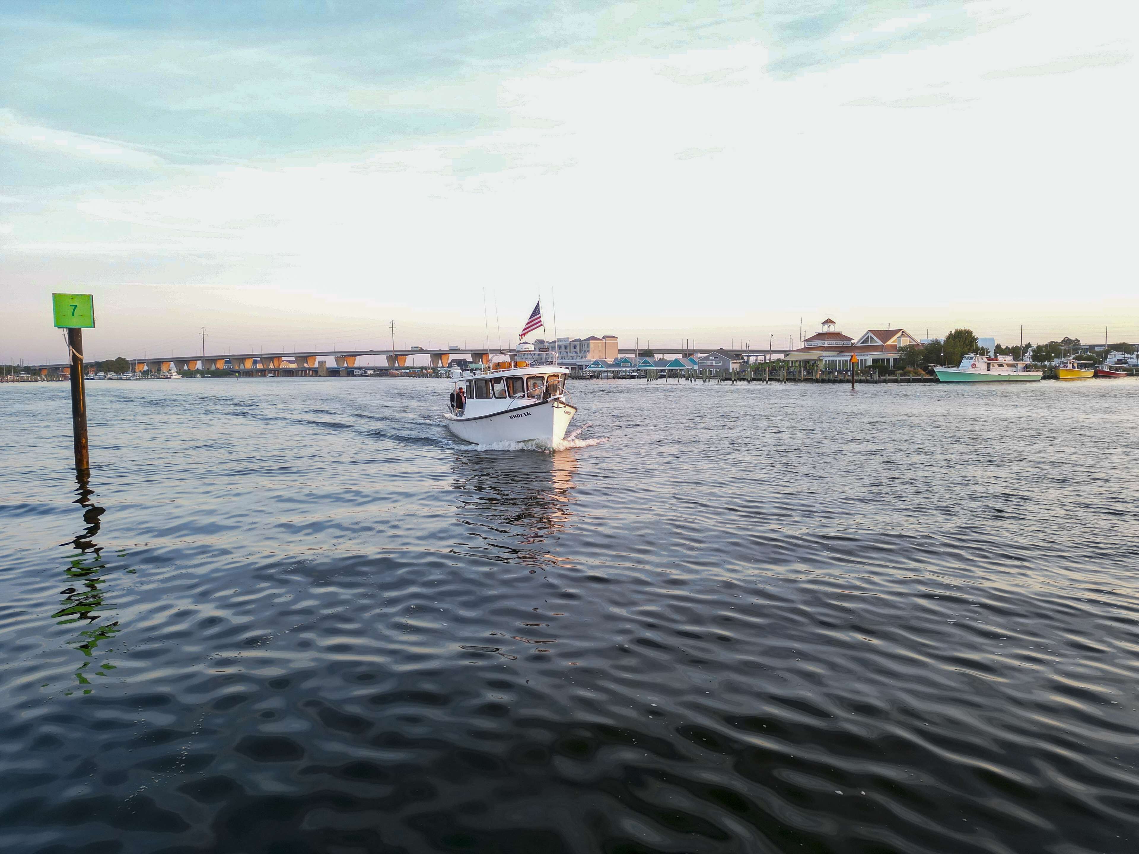 A boat on a calm river with a bridge in the background.