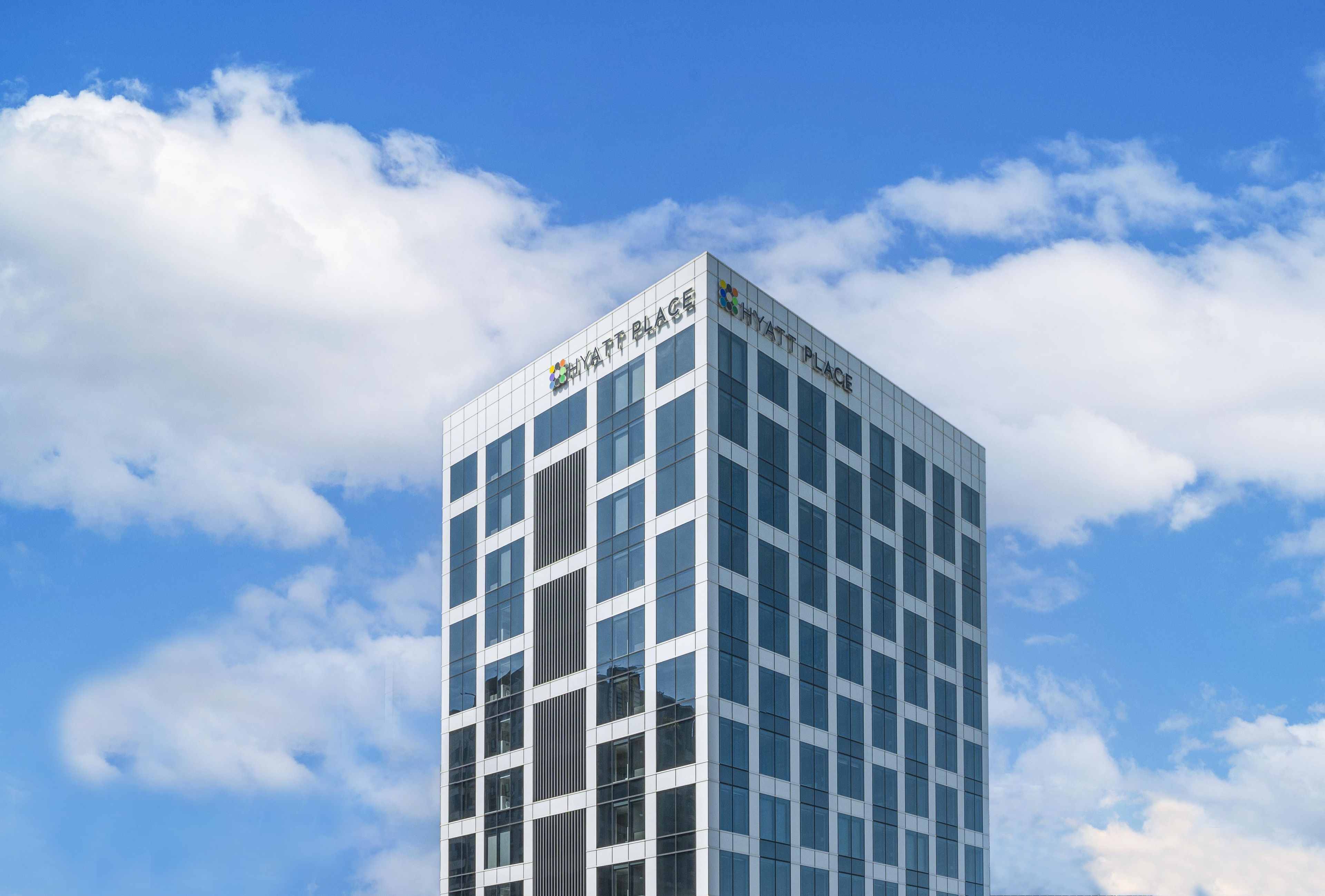 A modern hotel building with a glass facade and the name 'Hyatt Place' on the top.