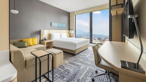 A hotel room with a bed, a desk, a sofa, a TV, and a large window with a city view. - Hyatt Place New Taipei City Xinzhuang (New Taipei City)