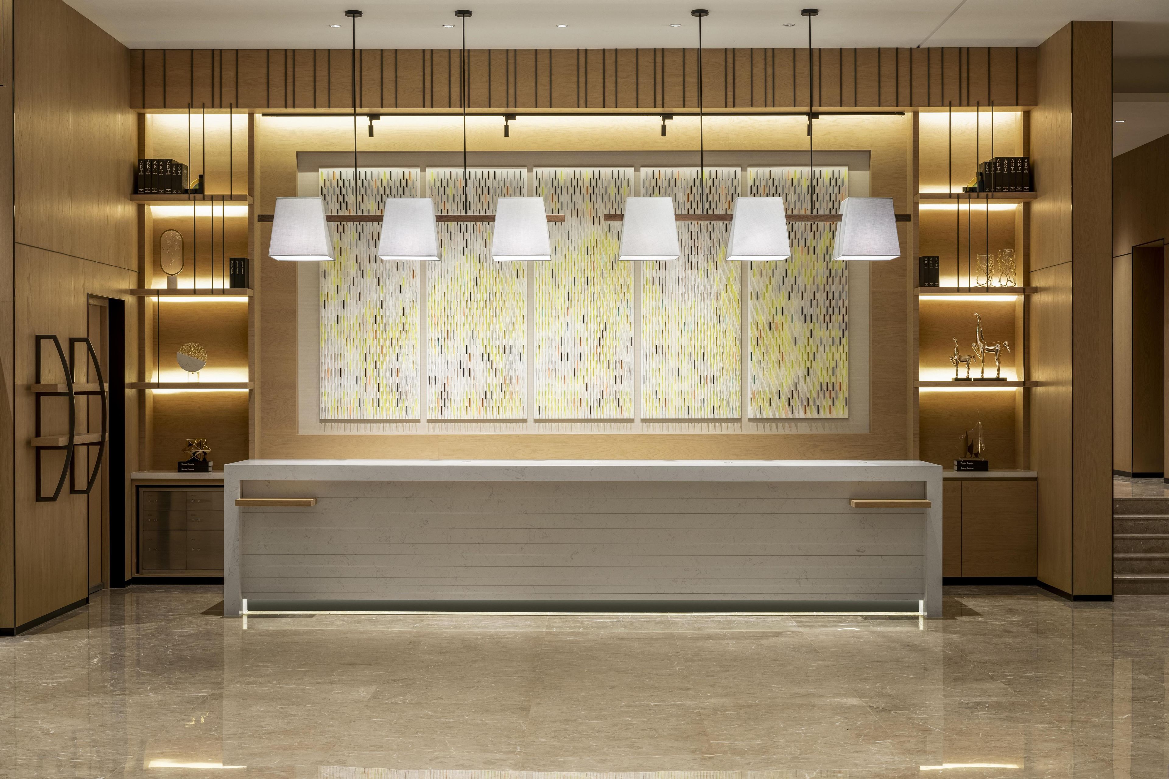 A modern reception area with a marble counter, pendant lighting, and a patterned wall.