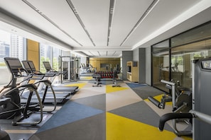 Un gimnasio con cintas de correr, máquinas de pesas y mancuernas.