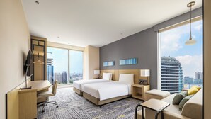 A hotel room with a large bed, a desk, a chair, a sofa, and a view of the city. - Hyatt Place New Taipei City Xinzhuang (New Taipei City)