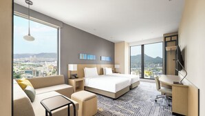 A hotel room with a large bed, a sofa, a desk, and a view of the city. - Hyatt Place New Taipei City Xinzhuang (New Taipei City)