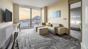 A modern hotel room with a large window offering a city view, a flat-screen TV, a sofa, a desk, and a bed. - Hyatt Place New Taipei City Xinzhuang (New Taipei City)