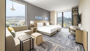 A modern hotel room with a large bed, a sofa, a desk, and a view of the city. - Hyatt Place New Taipei City Xinzhuang (New Taipei City)