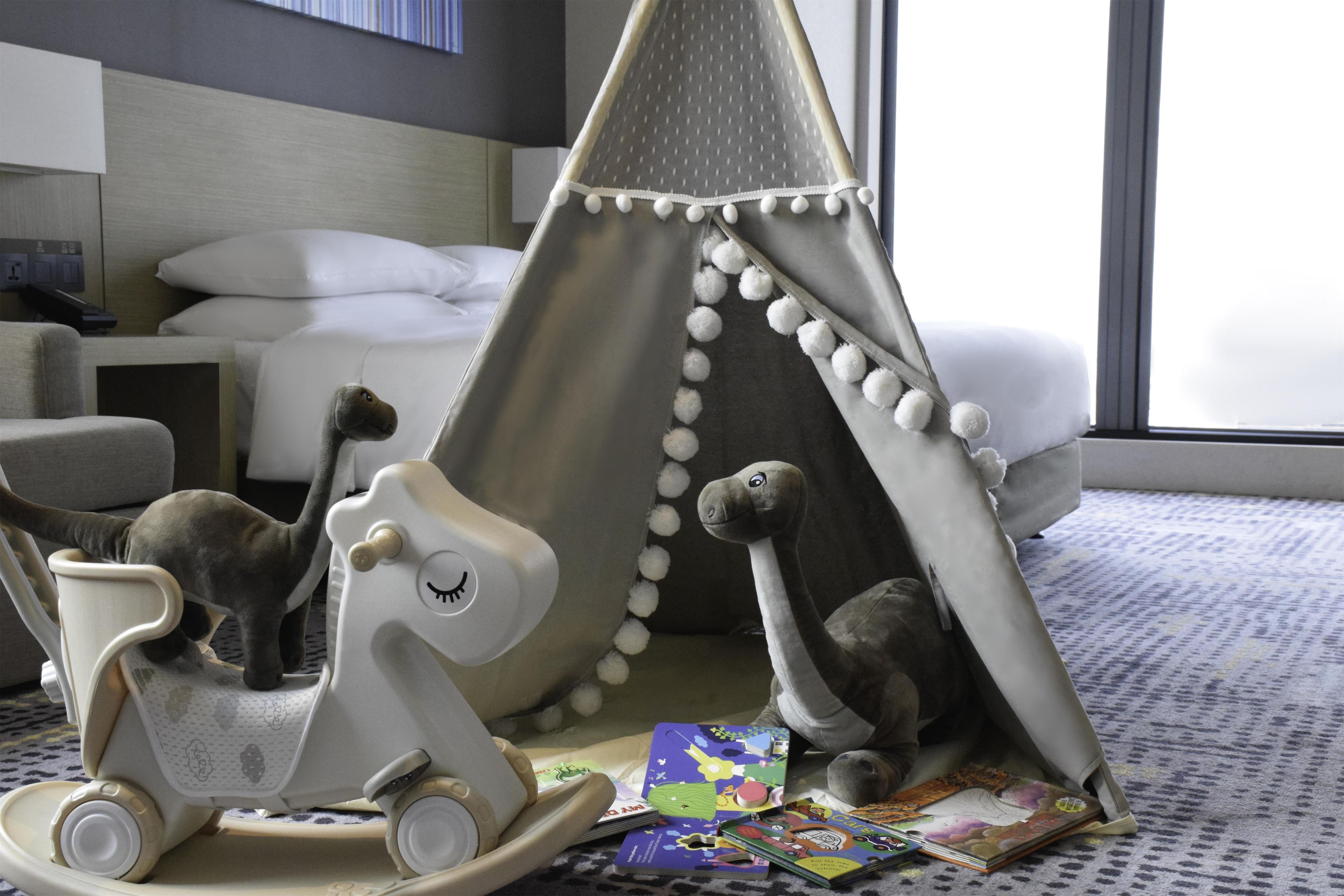 A child's play area with a tent, a rocking horse, and a pile of children's books.