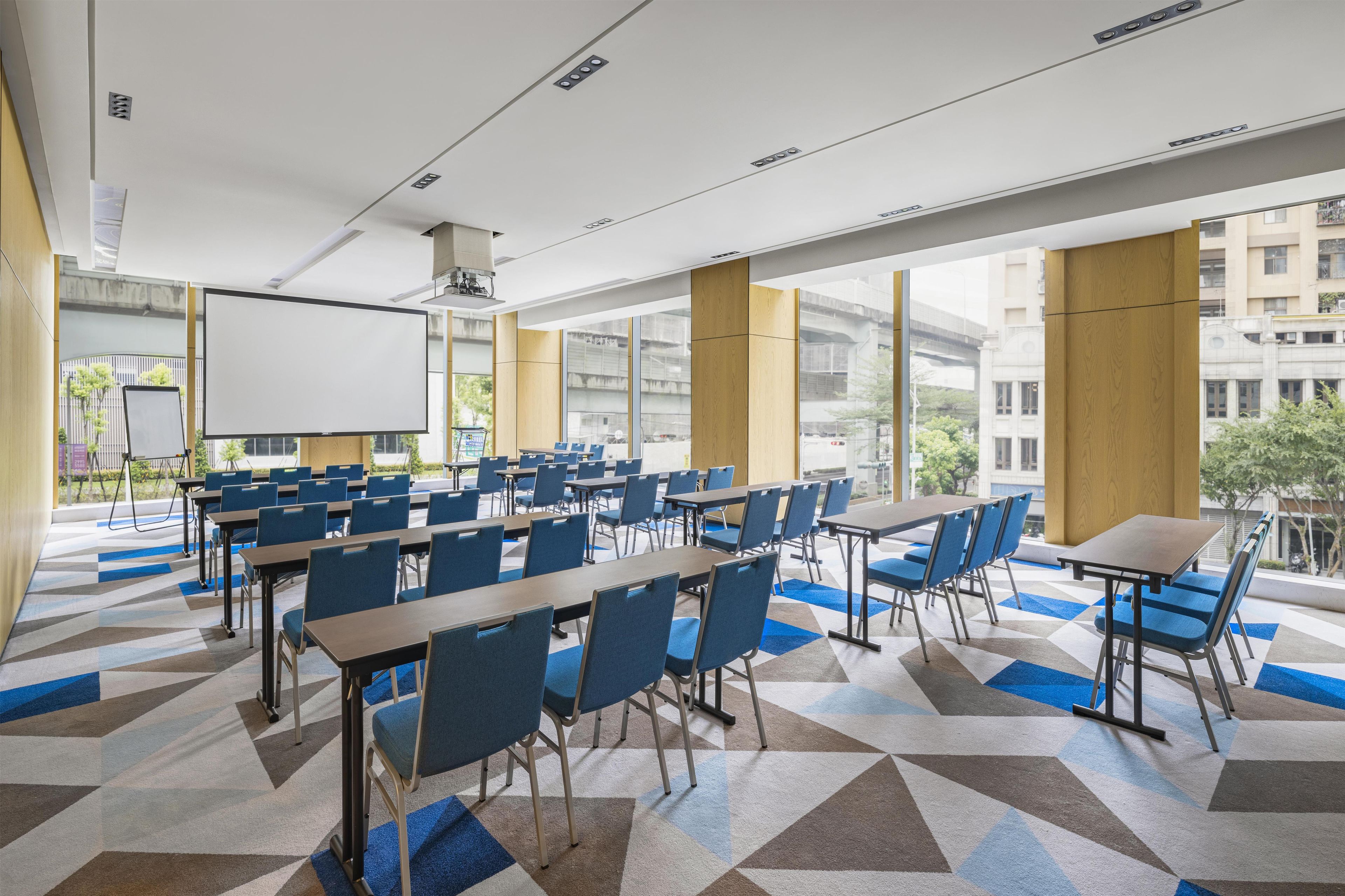 A conference room with tables and chairs, a whiteboard, and a large window with a view of buildings.