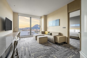A modern hotel room with a large window offering a city view, a flat-screen TV, a sofa, a desk, and a bed. - Hyatt Place New Taipei City Xinzhuang (New Taipei City)