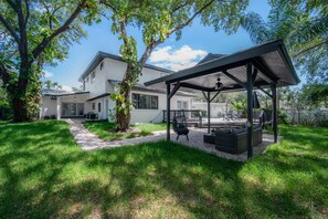 Relax in the serene backyard with a covered patio, outdoor furniture, and a large tree providing shade.