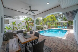 Relax by the pool surrounded by lush greenery and a brick patio.
