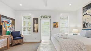 A bedroom with a bed, a chair, a desk, and artwork on the walls. - Anchor House- Heated Pool- 4 Bikes!- Prime Beach A (Santa Rosa Beach)
