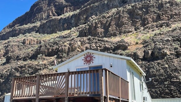 A white building with a balcony and a red sun emblem, surrounded by rocky terrain and mountains. - *Sunland Estates* Cozy quiet home (Quincy)