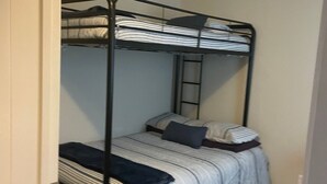 A bunk bed with a ladder, a striped bedspread, and a patterned rug in a room with plain walls. - *Sunland Estates* Cozy quiet home (Quincy)