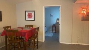 A dining area with a table set for four, a framed picture on the wall, and a hallway leading to a bedroom. - *Sunland Estates* Cozy quiet home (Quincy)