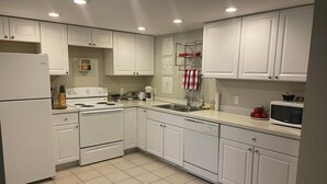 A modern kitchen with white cabinets, a stove, a sink, and a microwave. - *Sunland Estates* Cozy quiet home (Quincy)