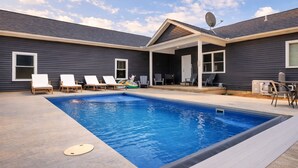 A backyard with a swimming pool, lounge chairs, and a covered patio area. - Serenity on Siverly: Saltwater pool and amazing view (McArthur)