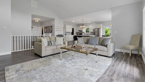 A spacious living room with a large coffee table, two sofas, and a chair. The room has a high ceiling with a ceiling fan and recessed lighting. - Serenity on Siverly: Saltwater pool and amazing view (McArthur)
