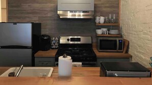 Une cuisine compacte équipée d’un réfrigérateur, d’une cuisinière, d’un four à micro-ondes et d’une machine à café.