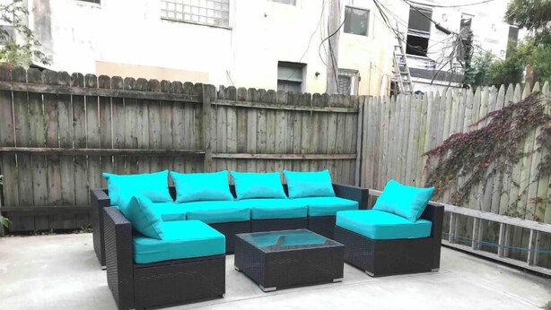 Un canapé modulable avec des coussins de couleur turquoise, placé dans un espace patio extérieur.