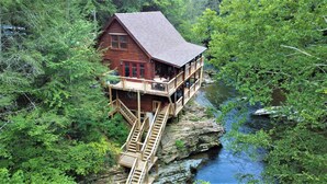 A cabin with a wooden exterior, a balcony, and a staircase leading to a deck.
