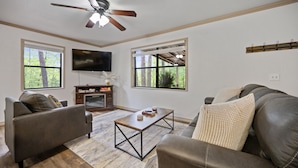 A living room with a ceiling fan, two sofas, a coffee table, and a flat-screen TV. - Deer Crossing Cabin Cabin in heart of Hochatown, 259, Broken Bow Lake (Broken Bow)