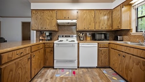 A kitchen with wooden cabinets, a stove, a microwave, and a dishwasher. - Deer Crossing Cabin Cabin in heart of Hochatown, 259, Broken Bow Lake (Broken Bow)