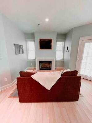 A living room with a red sofa, a fireplace, and a TV mounted above it.