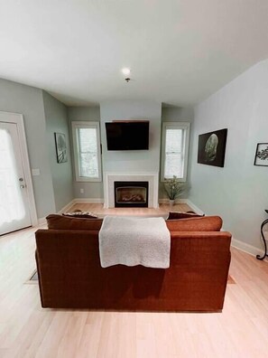 Una sala de estar con chimenea, sofá y televisor.