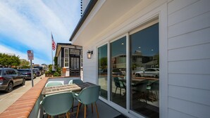 A patio with a table and chairs, a black door, and a large sliding glass door. - 3 Bedroom Renovated Condo on Balboa Island (Newport Beach)