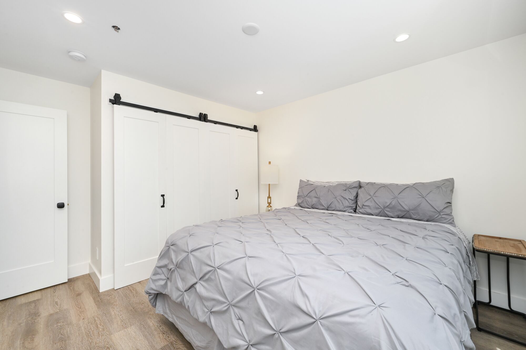 Un dormitorio con cama, armario, mesita de noche y lámpara.
