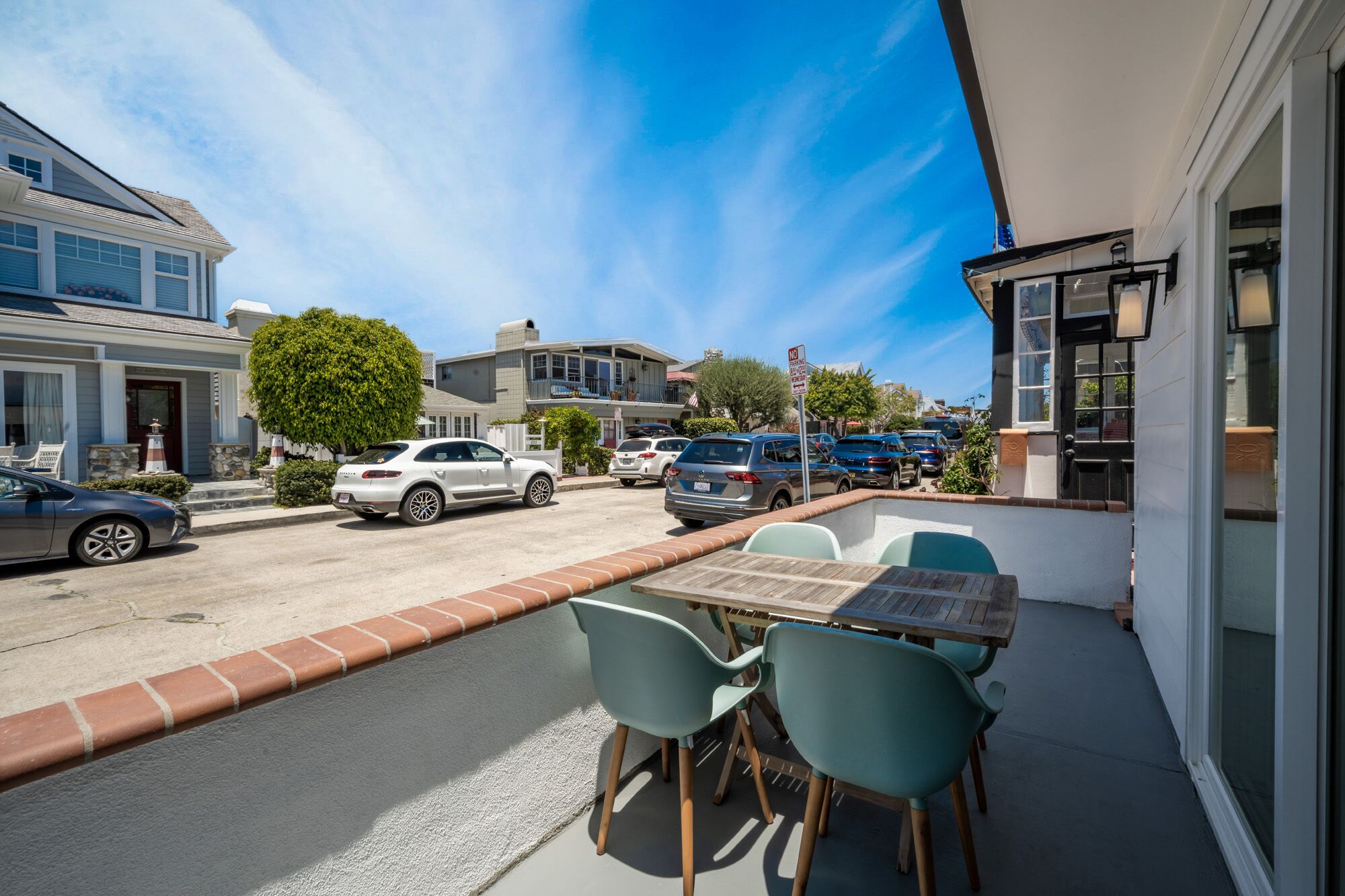 Une terrasse avec des sièges extérieurs, donnant sur la rue et bordée de voitures garées.