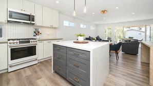 A modern kitchen with white cabinets, a built-in oven, and a central island with drawers.