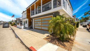 A modern two-story house with a garage, a flag, and a well-maintained lawn.