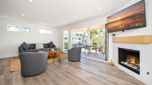 A modern living room with a fireplace, a sofa set, and a dining area.