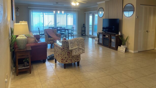 A spacious living room with a ceiling fan, a TV, and a dining area with a table and chairs. - Journey IMG CSF AMI Bradenton Sarasota SRQ (Anaheim)
