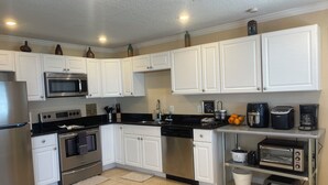 A modern kitchen with white cabinets, stainless steel appliances, and a black countertop. - Journey IMG CSF AMI Bradenton Sarasota SRQ (Anaheim)