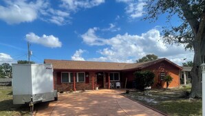 A single-story house with a brick facade, a front porch, and a driveway leading to the entrance. - Journey IMG CSF AMI Bradenton Sarasota SRQ (Anaheim)
