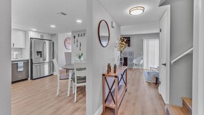 Eine moderne Küche mit Edelstahlgeräten, ein Essbereich mit Holztisch und -stühlen sowie eine Treppe zu einer weiteren Ebene.