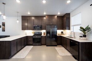 A modern kitchen with dark wood cabinets, stainless steel appliances, and a white countertop.