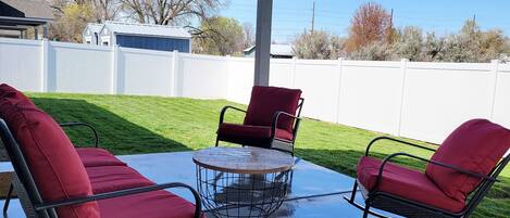 A covered patio with two rocking chairs and a small table.