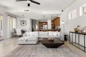 A modern living room with a sectional sofa, a coffee table, and a dining area with chairs.
