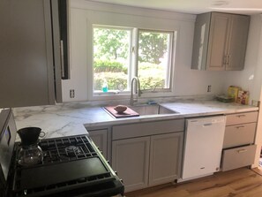 A kitchen with a stove, sink, and window.