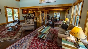 A spacious living area with a high ceiling, wooden beams, a large window, and a cozy seating arrangement. - Stunning Mountaintop Retreat with High End Amenities and Four Fireplaces (North Creek)